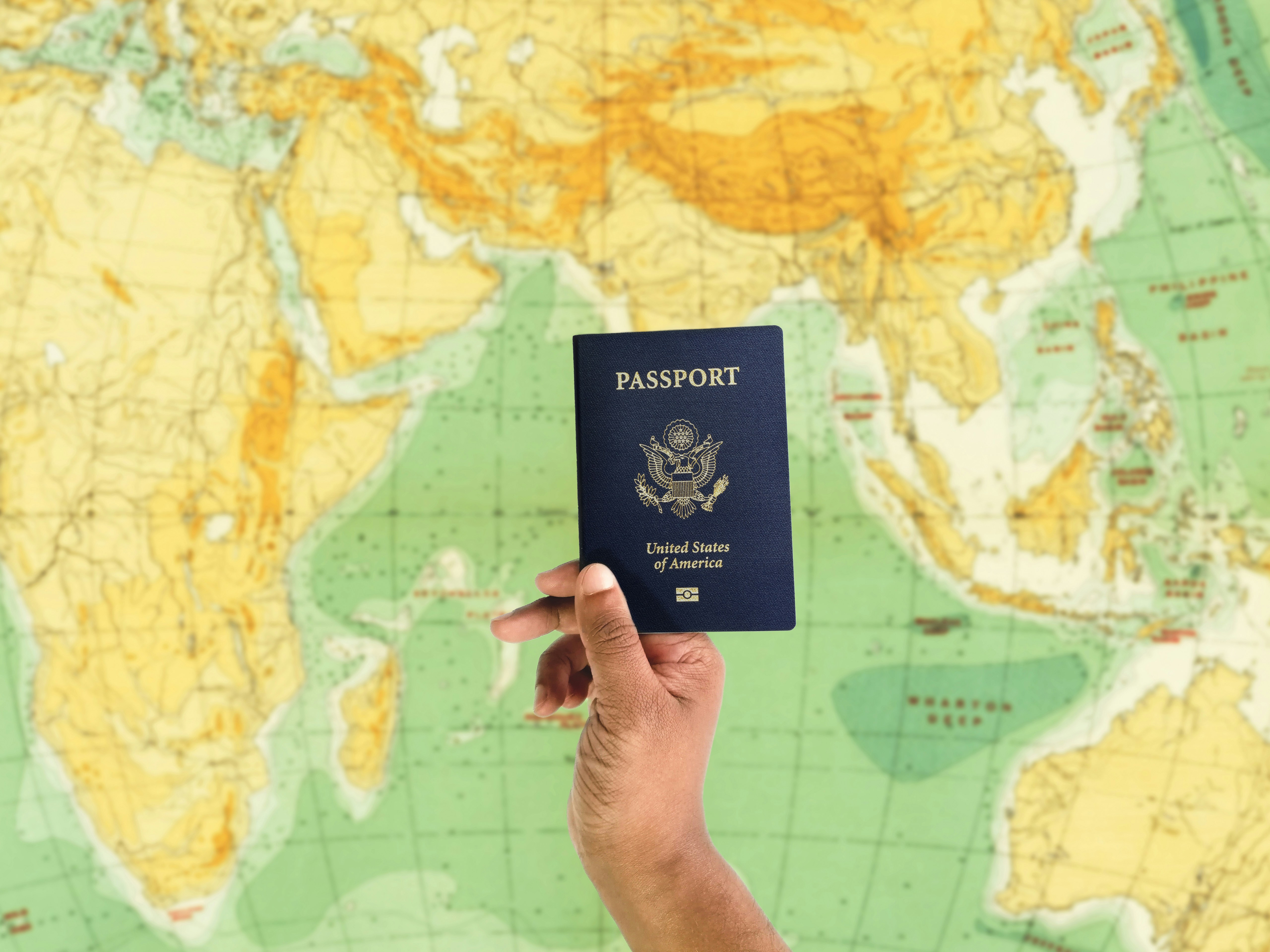 Hand holding a passport over a world map — visa consulting